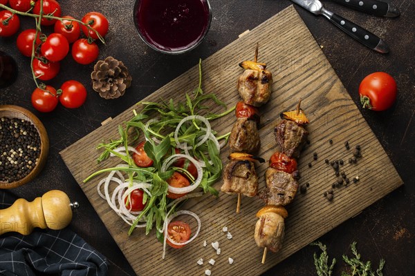 Grilled meat skewers and salad on cutting board