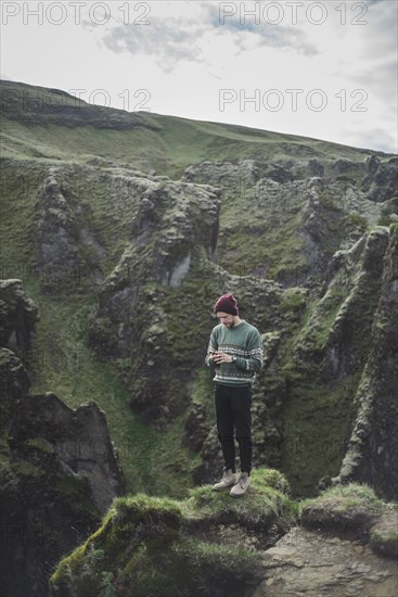 Man using smart phone on mountain in Kirkjubµjarklaustur