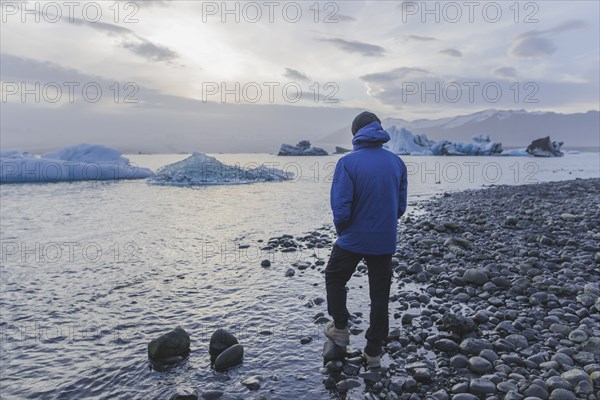 Man wearing blue coat by Jokulsarlon glacial lake in Iceland