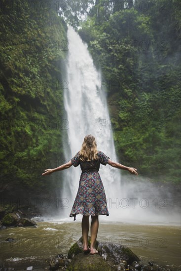 Woman standing by waterfall in Bali