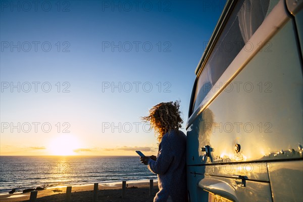 Woman using smart phone by beach at sunset in Fuerteventura