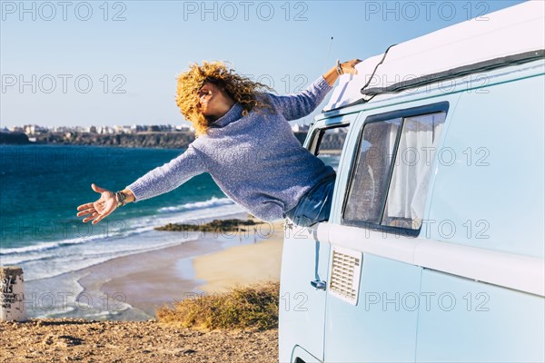 Woman leaning out of camper van window by beach in Fuerteventura