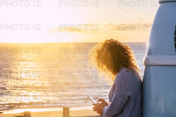 Woman using smart phone by beach at sunset in Fuerteventura