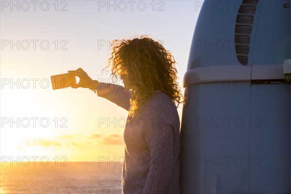 Woman taking selfie by camper van at sunset