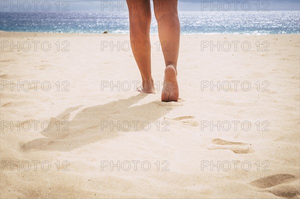 Barefoot woman walking on beach