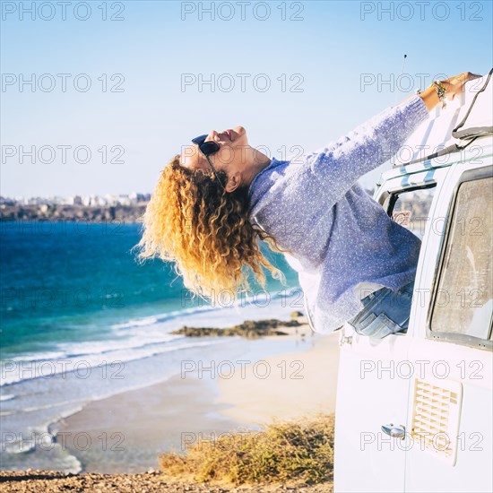 Woman leaning out of camper van window by beach in Fuerteventura