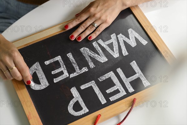 Woman writing 'Help Wanted' on chalkboard