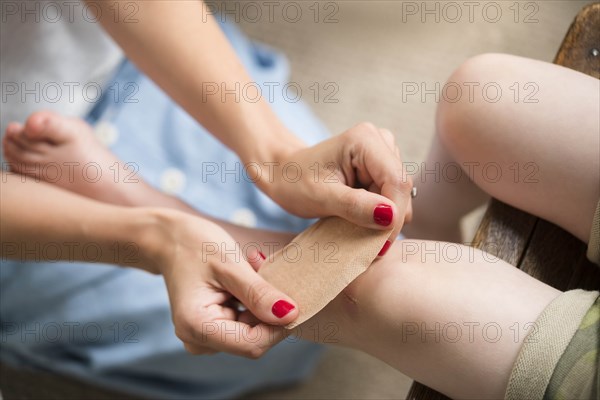 Mother putting bandage on her son's knee