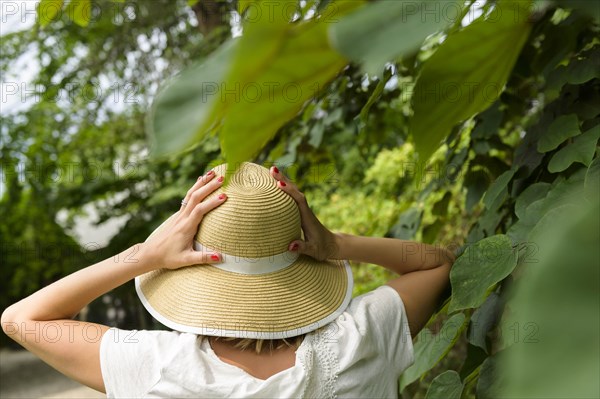 Woman wearing straw hat by trees