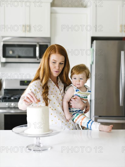 Mother and baby boy by birthday cake