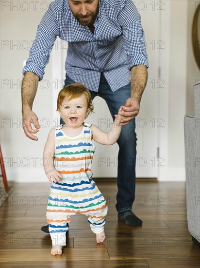 Father helping baby boy to walk