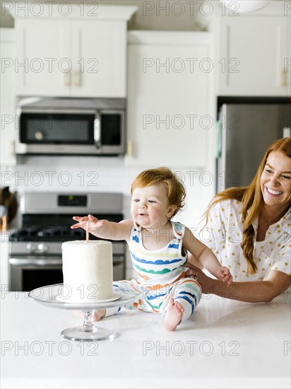 Mother and baby boy by birthday cake