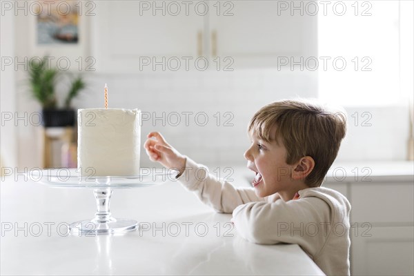 Boy reaching for birthday cake