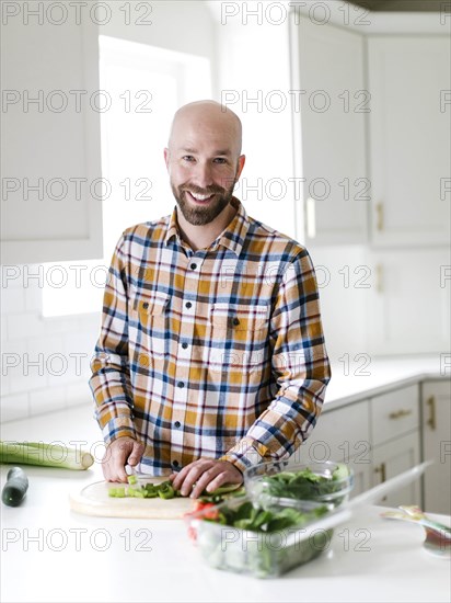 Smiling man chopping vegetables in kitchen