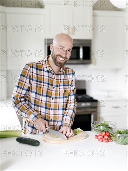 Smiling man chopping vegetables in kitchen