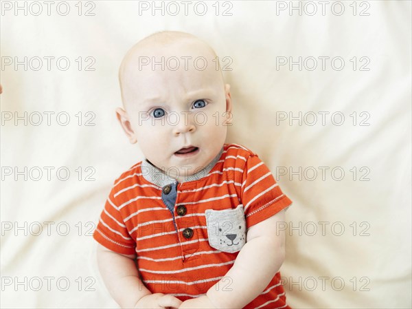 Confused baby boy lying on bed