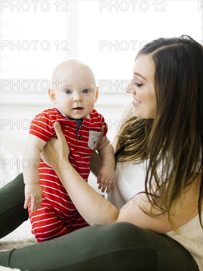 Smiling woman holding her son on bed