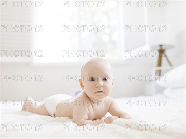 Shirtless baby boy lying on bed