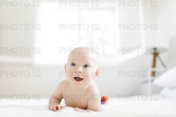 Shirtless baby boy lying on bed