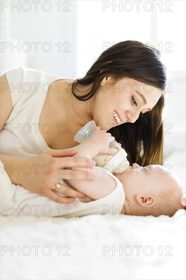 Mother watching her baby boy drink milk from bottle