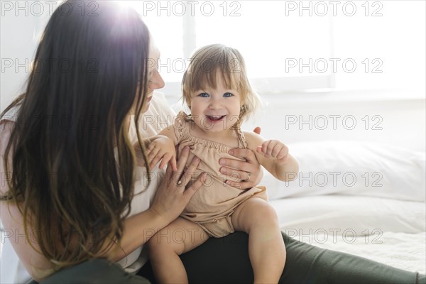 Woman holding her daughter on bed