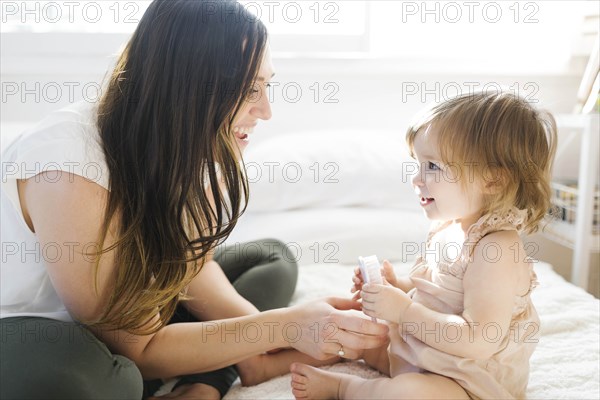 Mother and daughter on bed with hairbrush