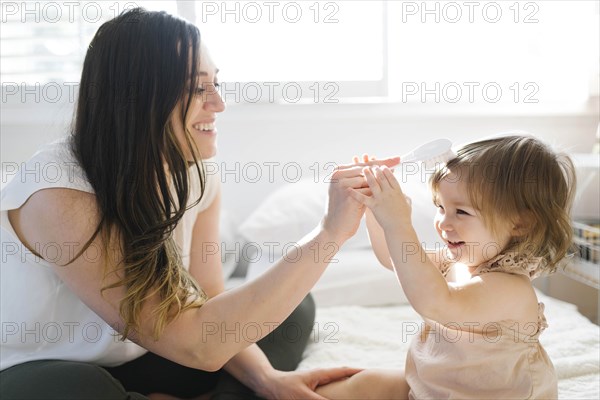 Mother and daughter on bed with hairbrush