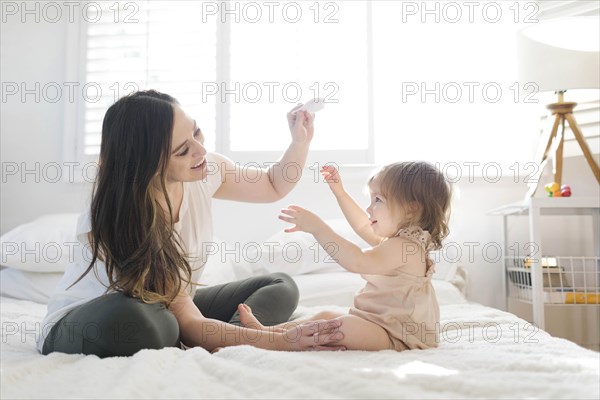 Mother and daughter on bed with hairbrush