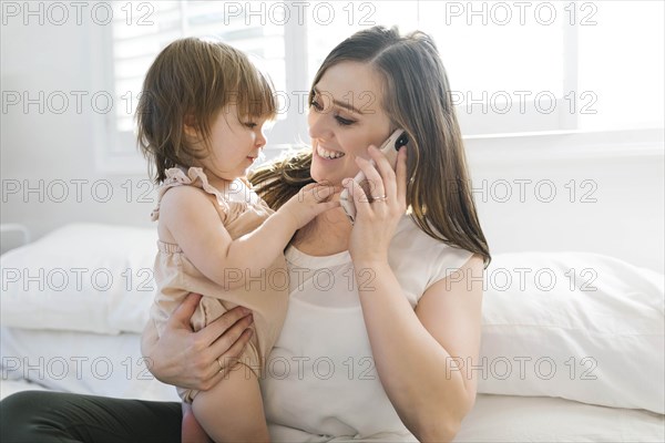 Woman holding daughter while on phone call