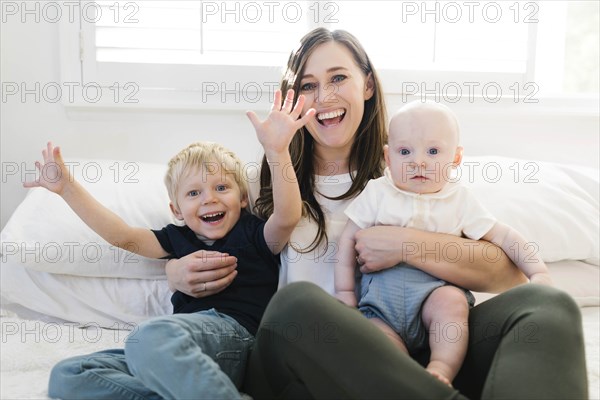 Smiling woman and her sons on bed