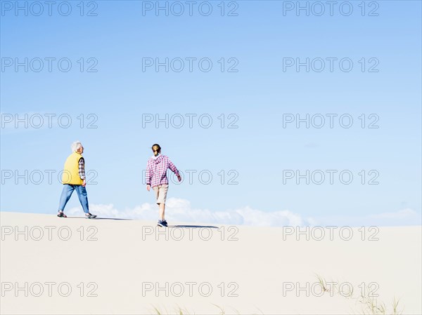 Mother and daughter walking on sand dune in Hawke's Nest, New South Wales, Australia