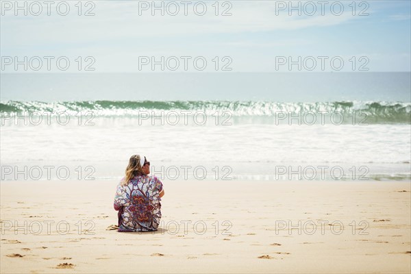 Woman sitting on beach in Lisbon, Portugal