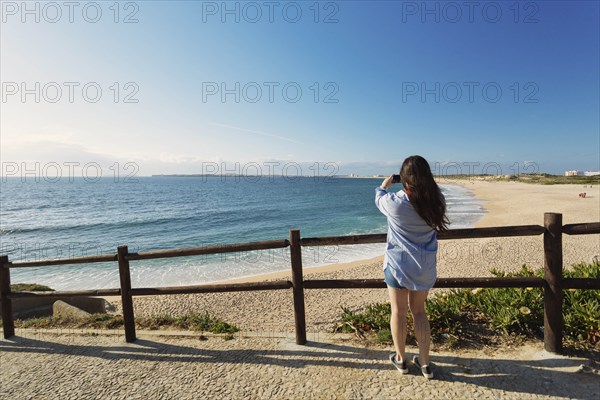 Woman photographing beach in Lisbon, Portugal