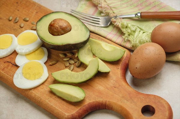 Avocado, egg and sunflower seeds on cutting board