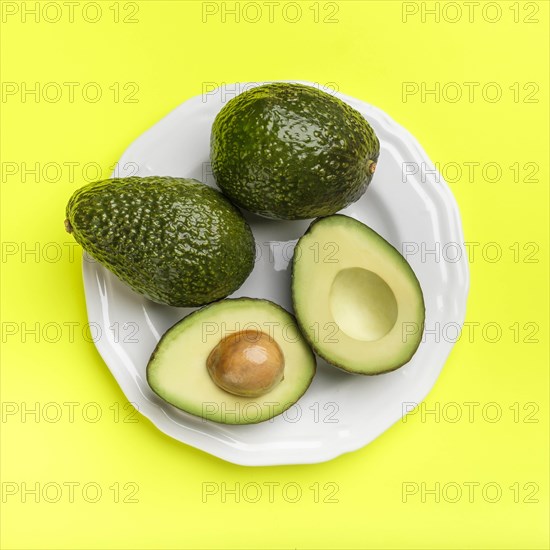 Plate of avocados on green surface