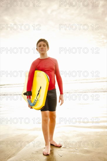 Boy holding body board on beach