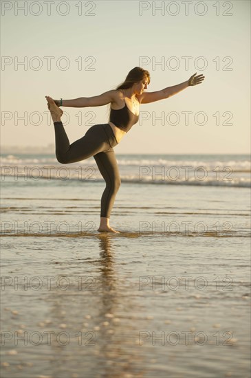 Young woman doing yoga on beach