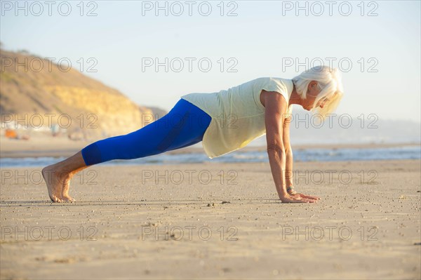 Mature woman doing push-ups on beach