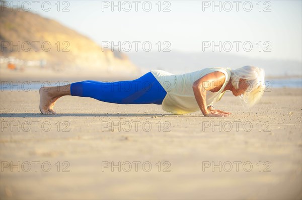 Mature woman doing push-ups on beach