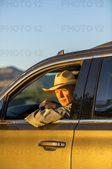 Farmer wearing cowboy hat driving SUV