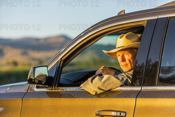 Farmer wearing cowboy hat driving SUV