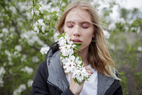 Young woman with her eyes closed holding white blossoms