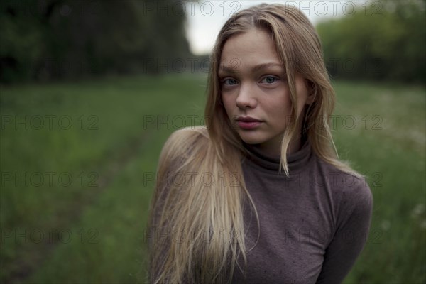 Portrait of young woman with blond hair in field