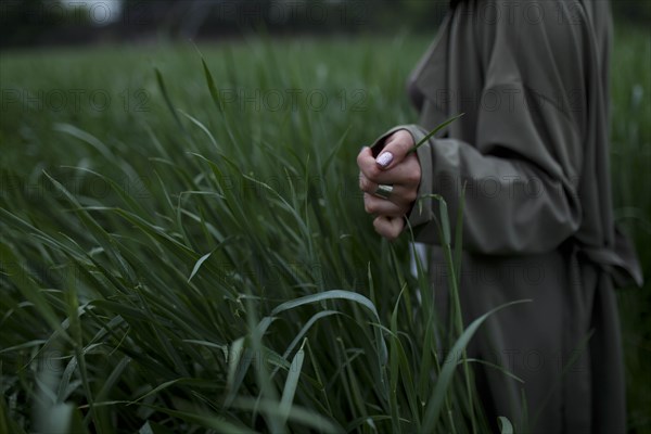 Woman wearing green coat walking through field