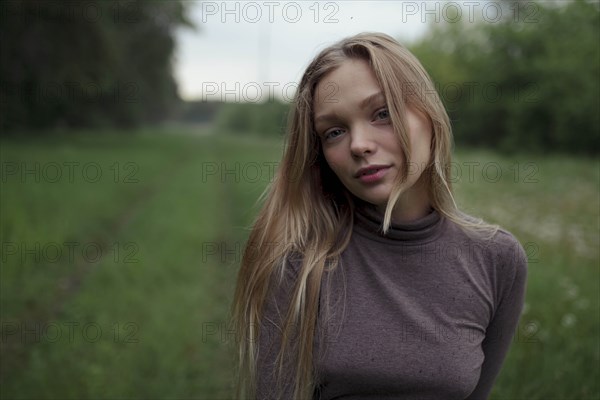 Portrait of young woman with blond hair in field