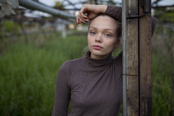 Young woman leaning on wooden post