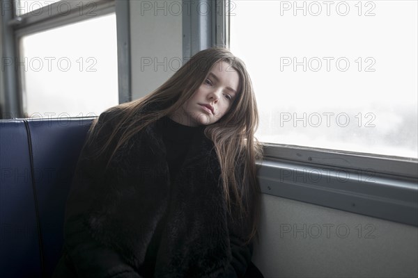 Young woman wearing black fur coat on train