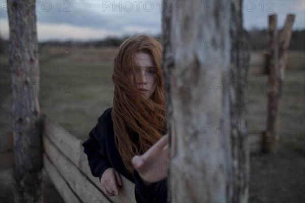 Windswept teenage girl by tree trunk