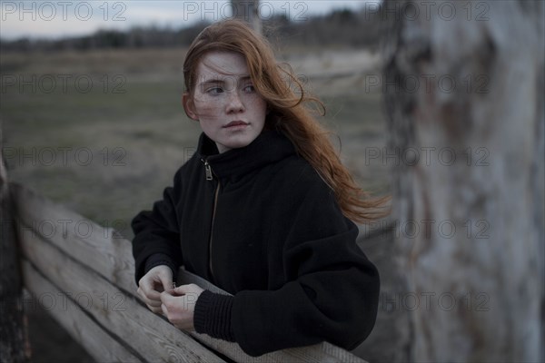 Windswept teenage girl by tree trunk