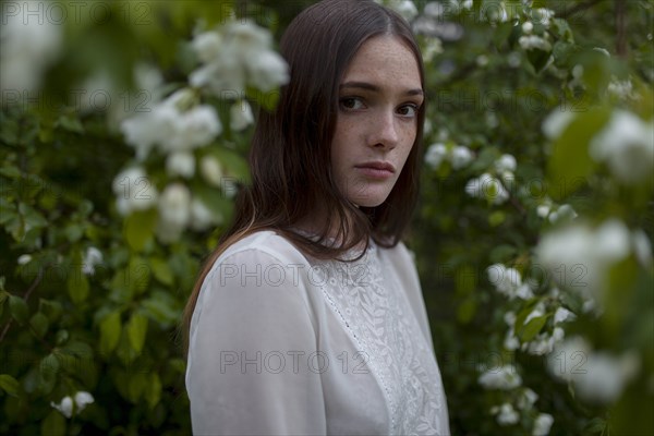 Young woman among white blossoms